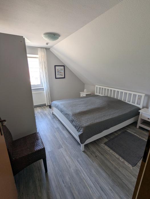 Schlafzimmer 1 mit weißem Kingsize-Bett, Nachttischen und Fenster