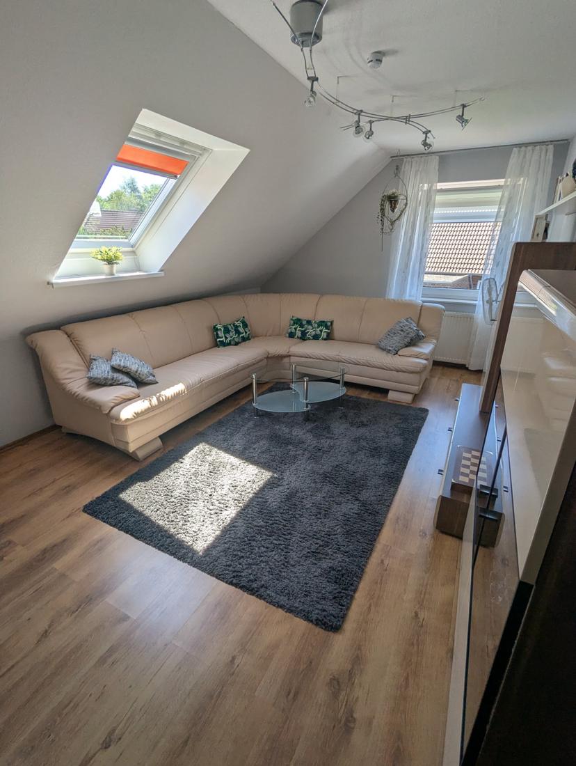 Helles Wohnzimmer mit großem Ecksofa, Glastisch und Dachfenster